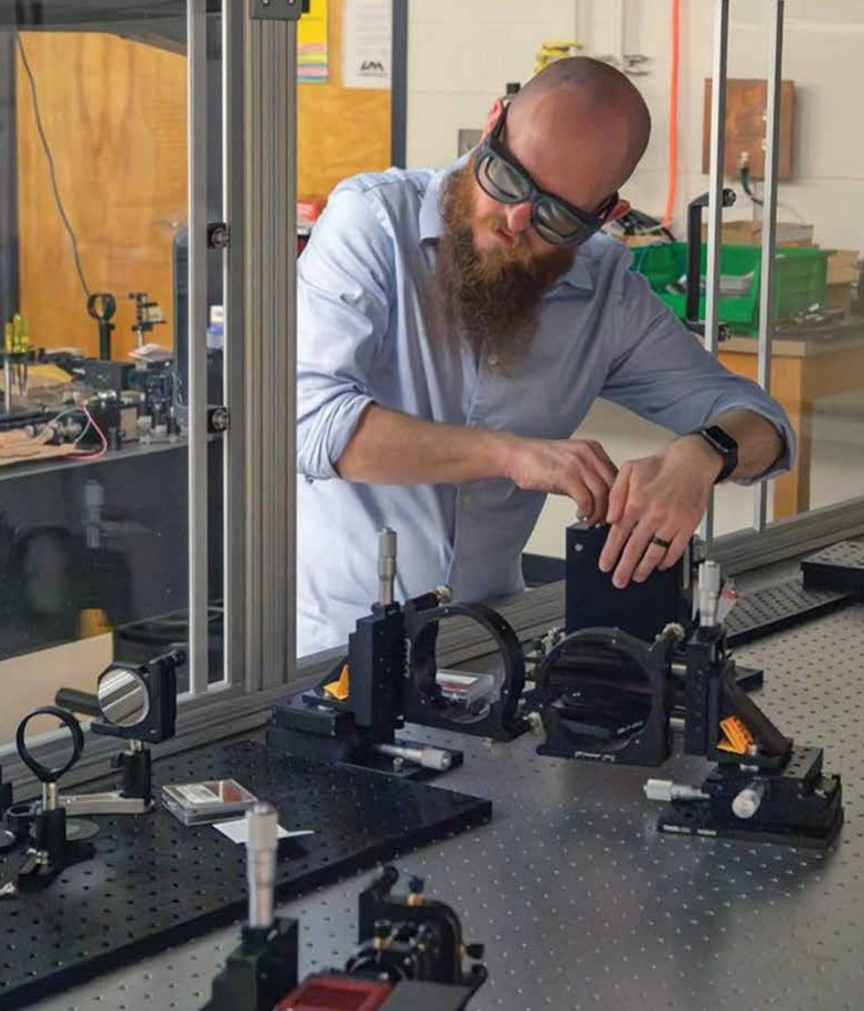 A man works on series of lasers on a tabletop system.